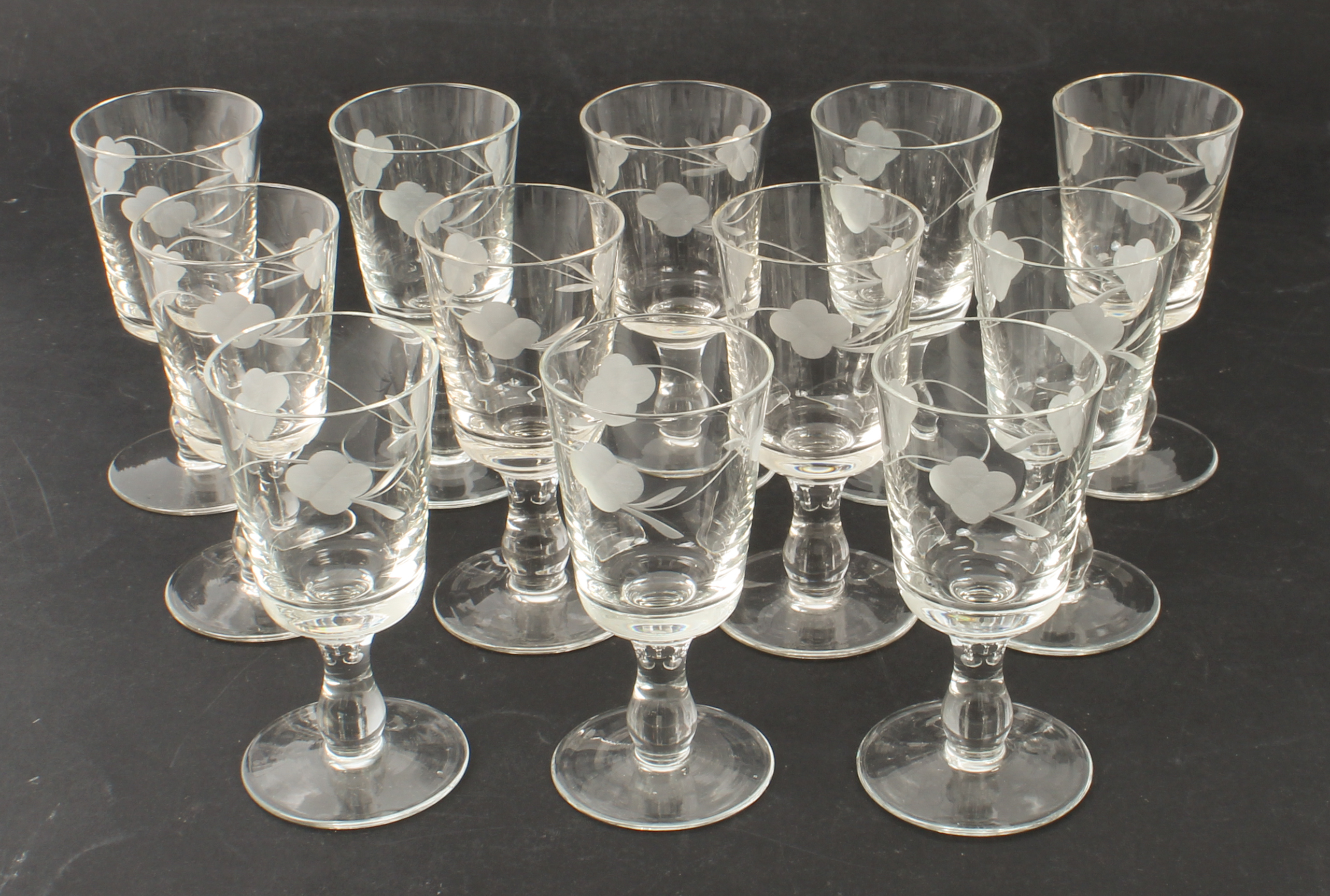 A set of twelve port glasses - 1950s-60s, the bucket bowls wheel-engraved with trailing flowers,