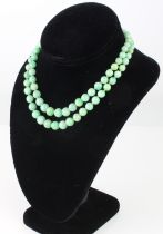 A mid-century two strand mottled apple green jade necklace - the beads graduating from 5mm to 9mm,