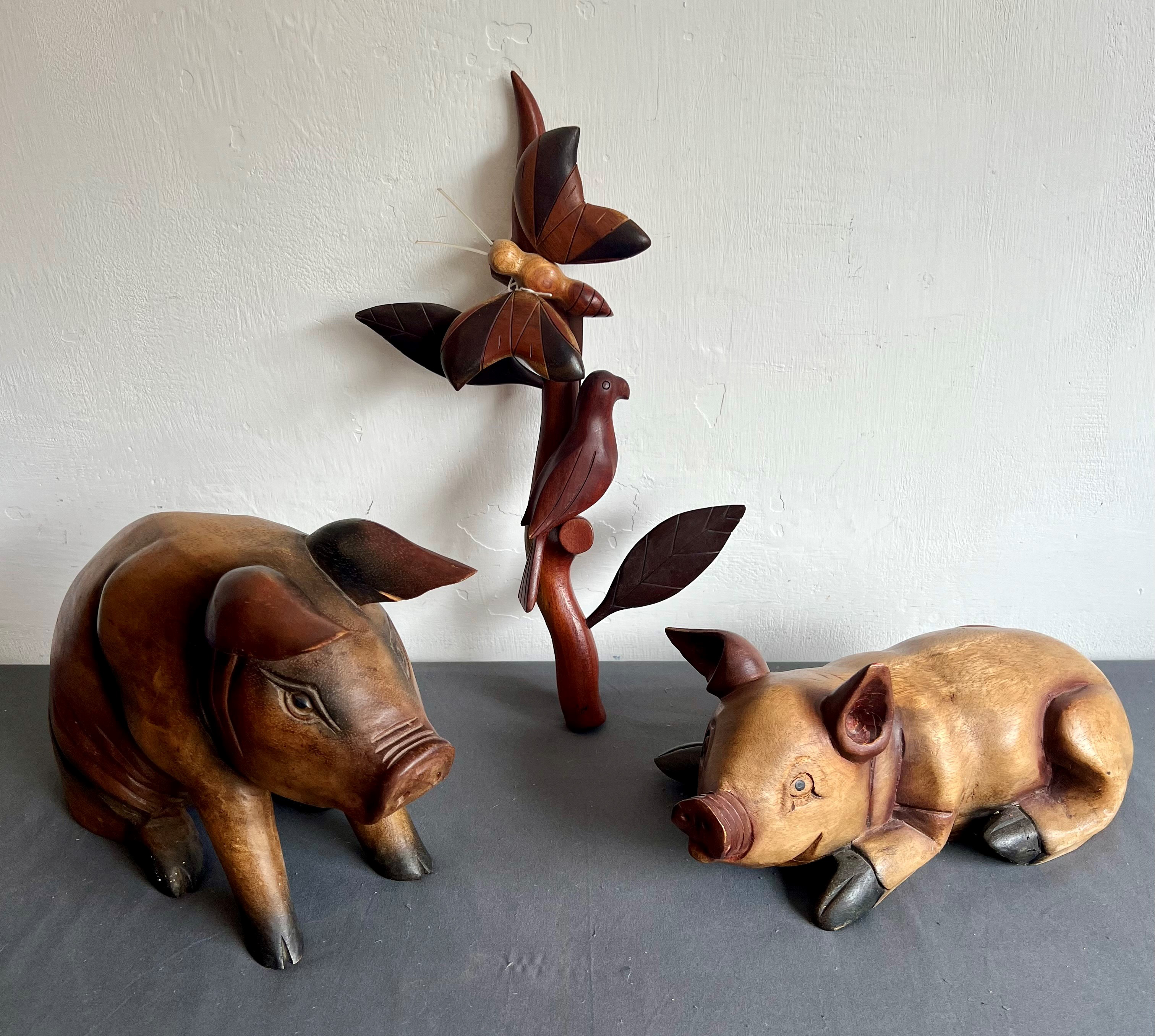 Two large carved wooden pigs - the seated pig 24 cm high; together with a carved wooden parrot and