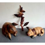 Two large carved wooden pigs - the seated pig 24 cm high; together with a carved wooden parrot and