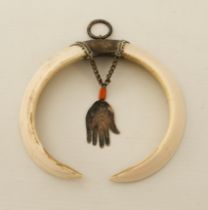 An Indian Hindu tusk and white metal pendant - the tusks from a wild boar, the white metal and brass