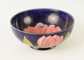 A Moorcroft 'Magnolia' pattern footed bowl - with pink flowers on a dark blue ground, painted