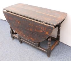 An early 18th century oak gateleg dining table - the oval dropflap top raised on baluster and bobbin