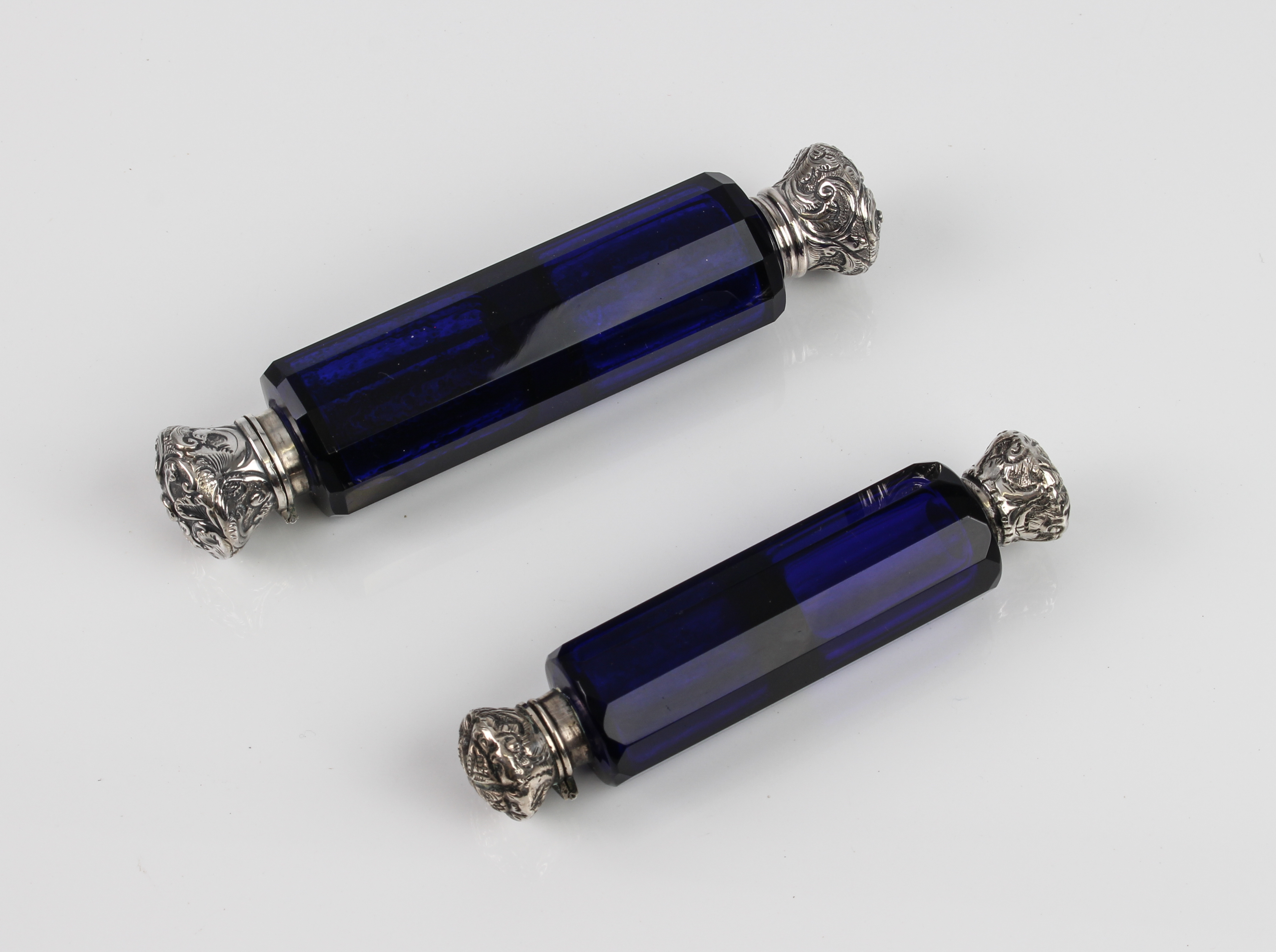 Two Victorian blue cut-glass blue double-ended scent bottles - with white-metal tops, one hinged,