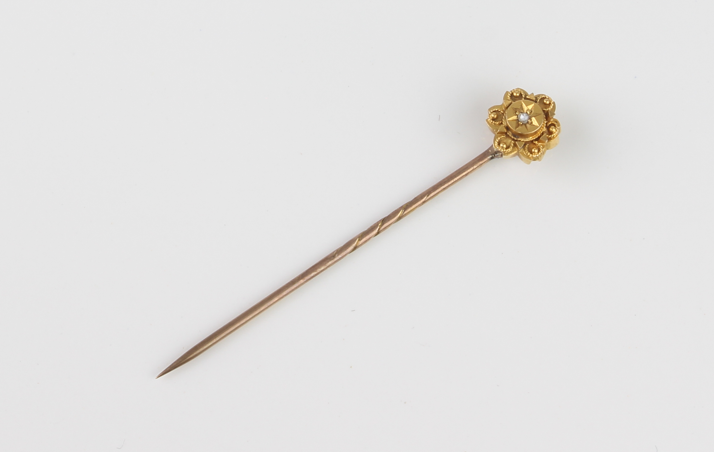 A cased Victorian yellow and rose gold and diamond stick pin - the 18ct yellow gold daisy head set