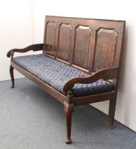 An 18th century four-panel joined oak settle - the back with four serpentine, chamfered panels, over