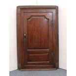 A mid-18th century oak wall-hanging corner cupboard - with two-panel door and fluted canted corners,