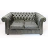 A green leather two-seater Chesterfield sofa - raised on four bun feet (LWH 148 x 87 x 71 cm)