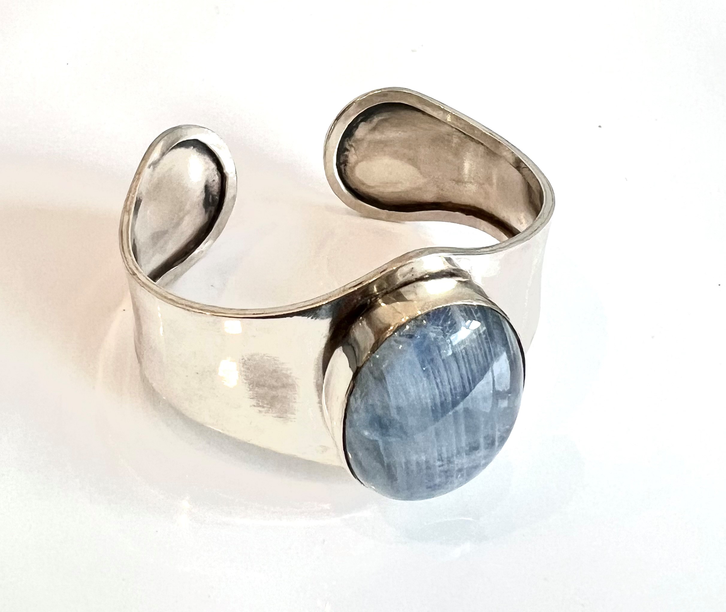A silver and blue moonstone bangle - the shaped bangle set to the centre with a large oval