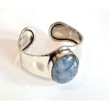 A silver and blue moonstone bangle - the shaped bangle set to the centre with a large oval