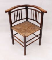 An Edwardian beech wood spindle-back corner chair - with horseshoe arms and rush seat, on square