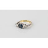 An 18ct white and yellow gold, sapphire and diamond three stone ring - the central 7mm round cut