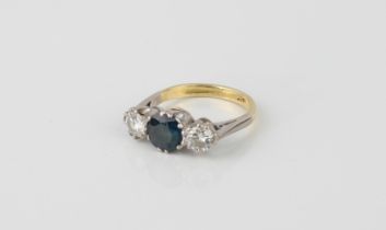 An 18ct white and yellow gold, sapphire and diamond three stone ring - the central 7mm round cut