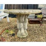 A composite stone garden table - the circular top with moulded lappet edge, on a pedestal base