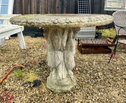 A composite stone garden table - the circular top with moulded lappet edge, on a pedestal base