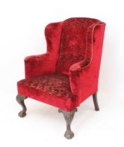 A George II style carved mahogany wingback armchair - first half 20th century, upholstered in dark-