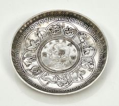 A Chinese white metal zodiac dish - inset with a Chinese $1 one dollar coin, within a flowerhead