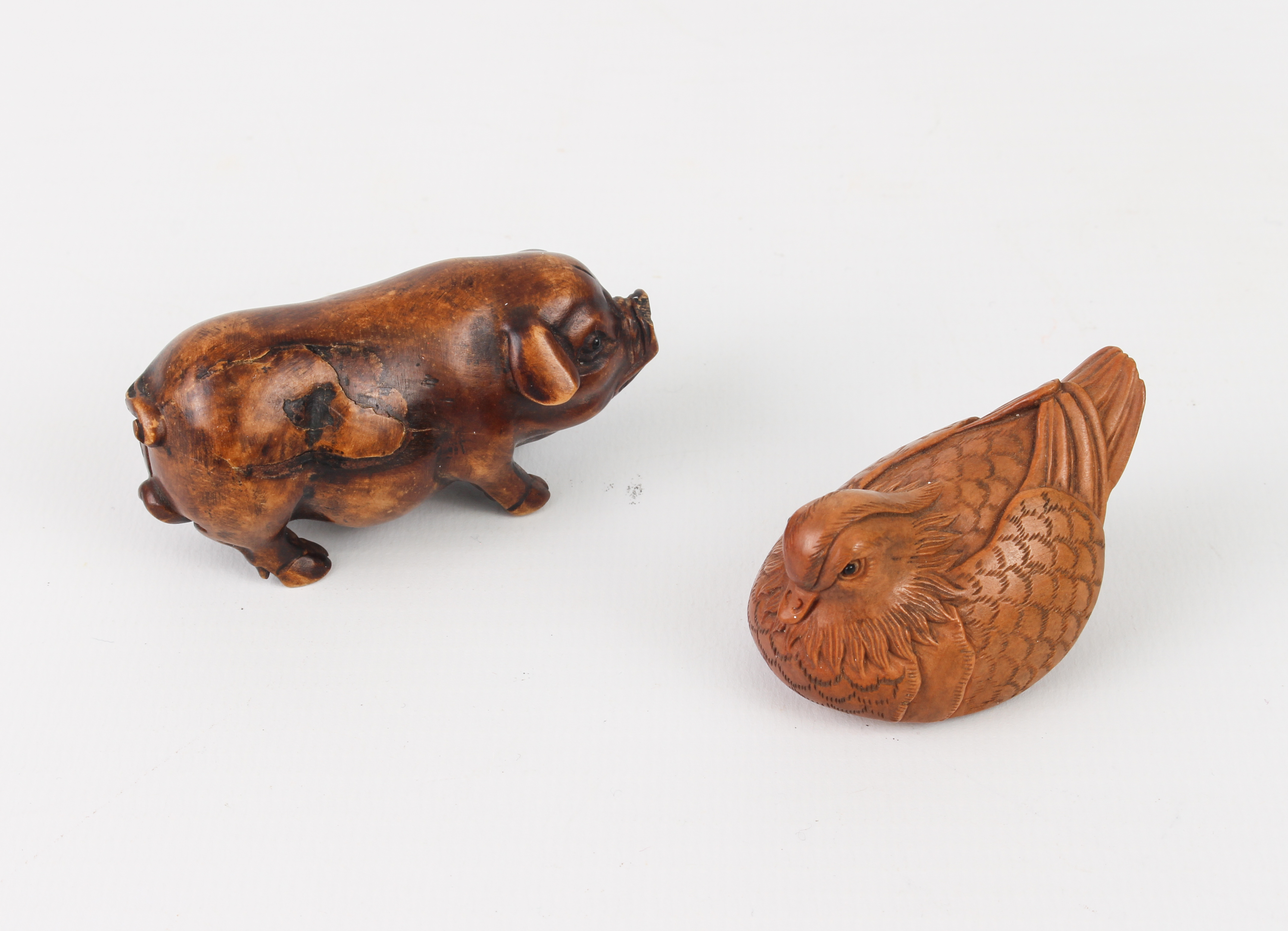 A carved fruitwood Okimono of a pig, plus a carved and signed netsuke of a Mandarin duck.