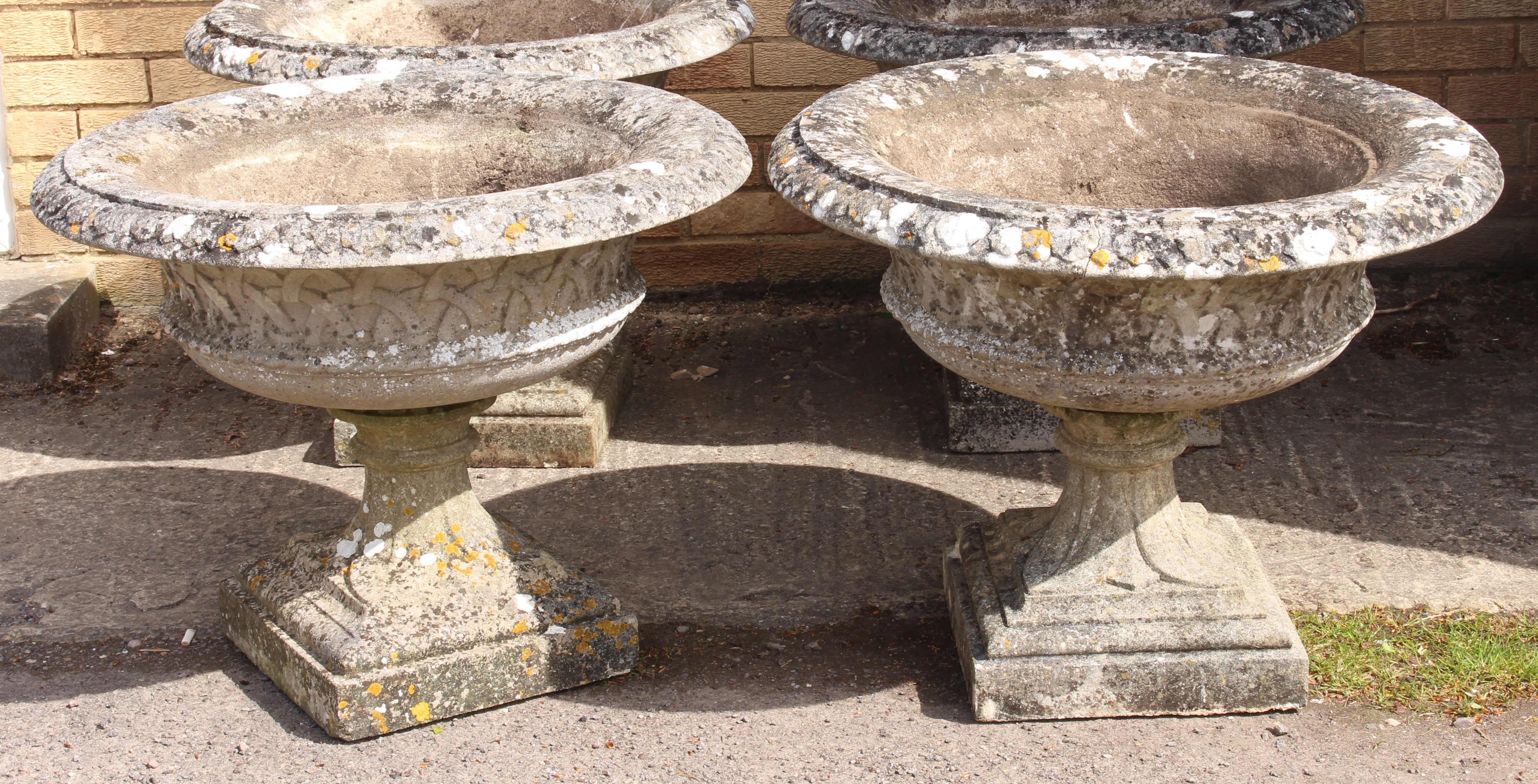 A pair of large composite stone campana style garden urns - well weathered, decorated with foliage