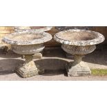 A pair of large composite stone campana style garden urns - well weathered, decorated with foliage