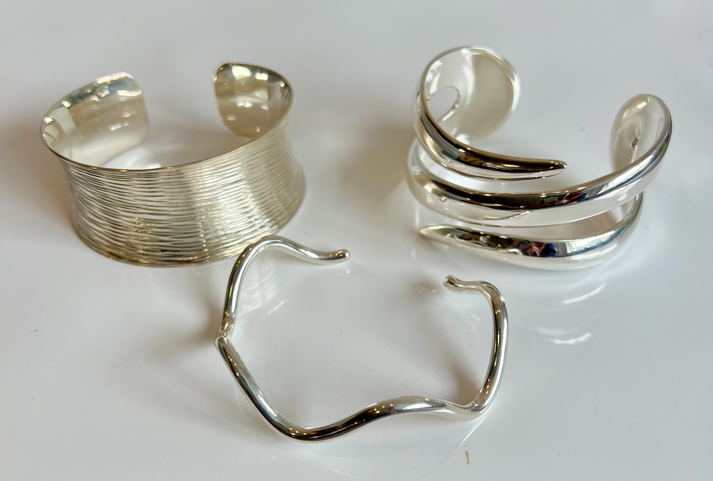 Three modernist sterling silver bangles - each stamped 925, comprising a bark effect cuff bangle,