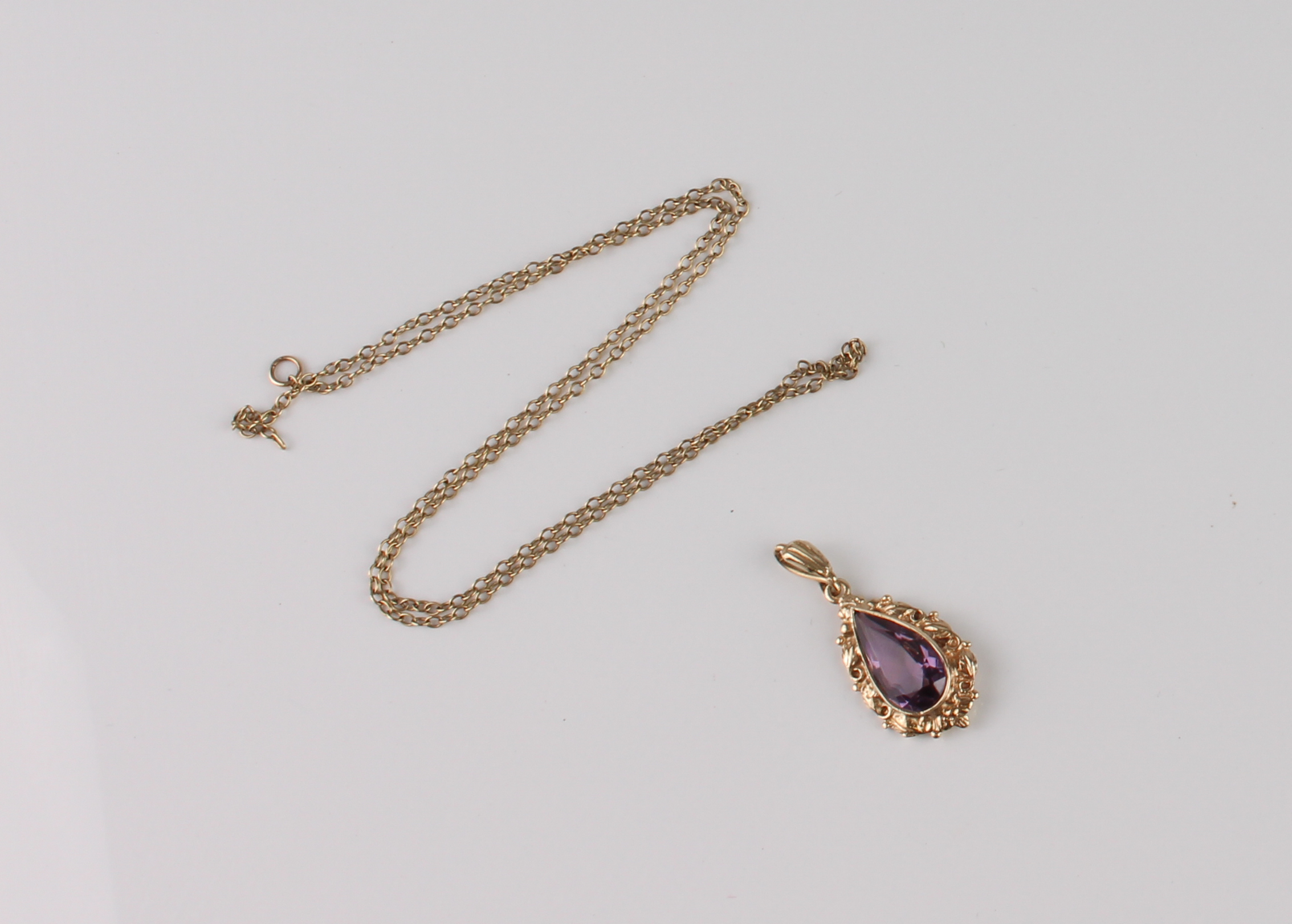 A 9ct gold and amethyst pendant - the pear cut amethyst, approx. 14.5 x 7.5mm, in a foliate scroll - Image 2 of 2