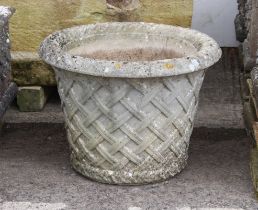 A  composite stone garden planter - well weathered, of tapering cylindrical form, interlaced lattice