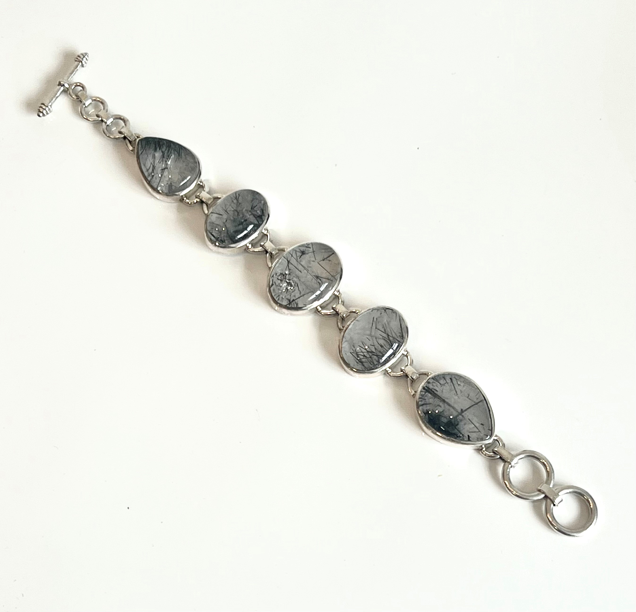 A silver and rutilated quartz bracelet - with five oval and teardrop cabochon stones in rub-over