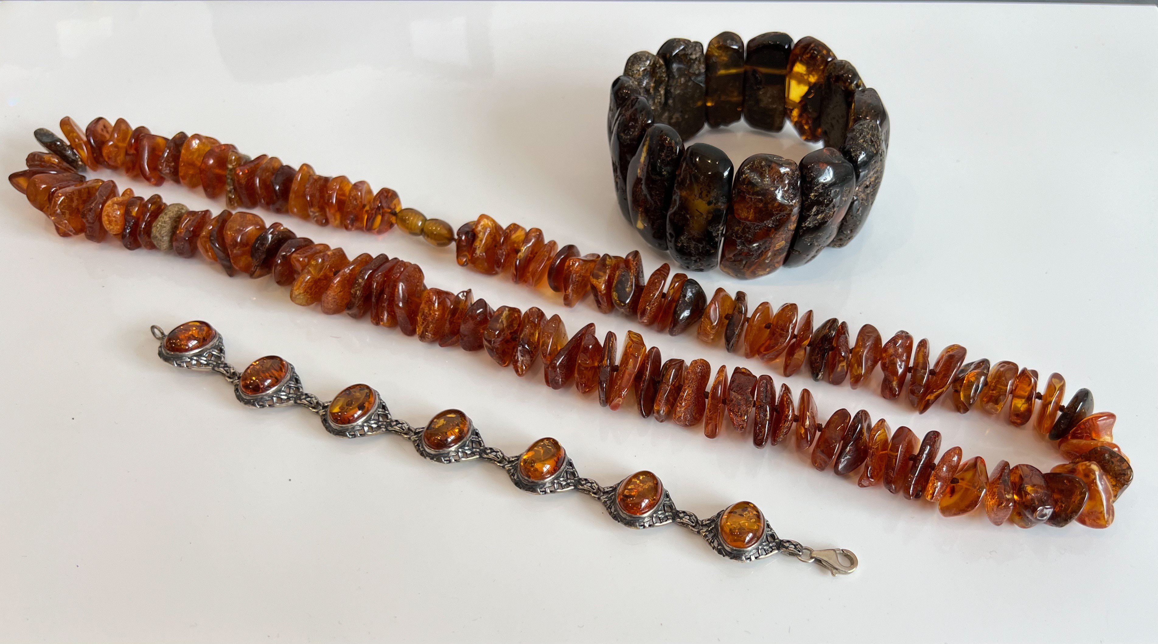 A silver and amber bracelet - with seven oval cabochon amber stones within pierced lattice