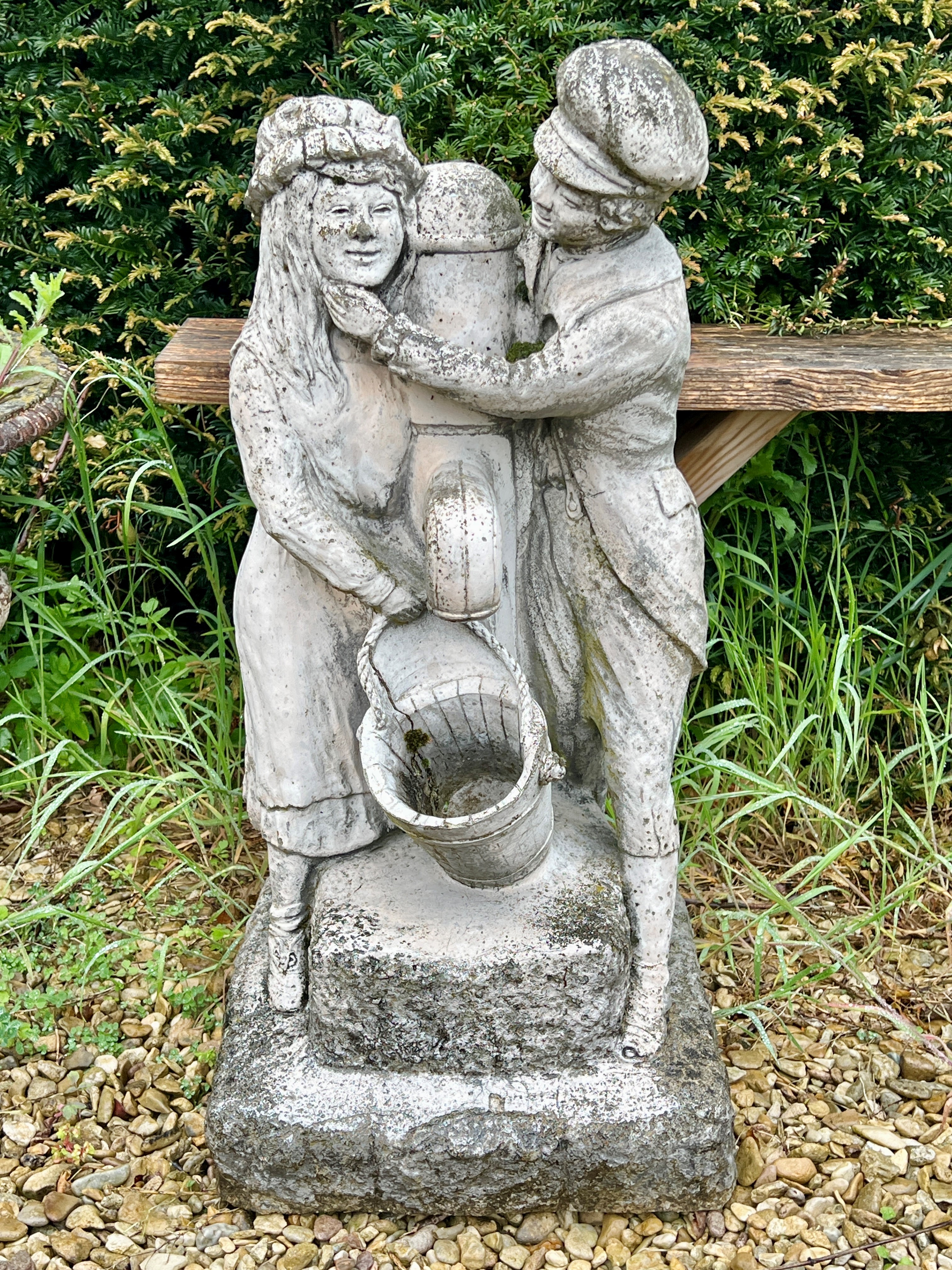 A composite stone water feature - depicting a couple standing beside a water tap, 76cm high.