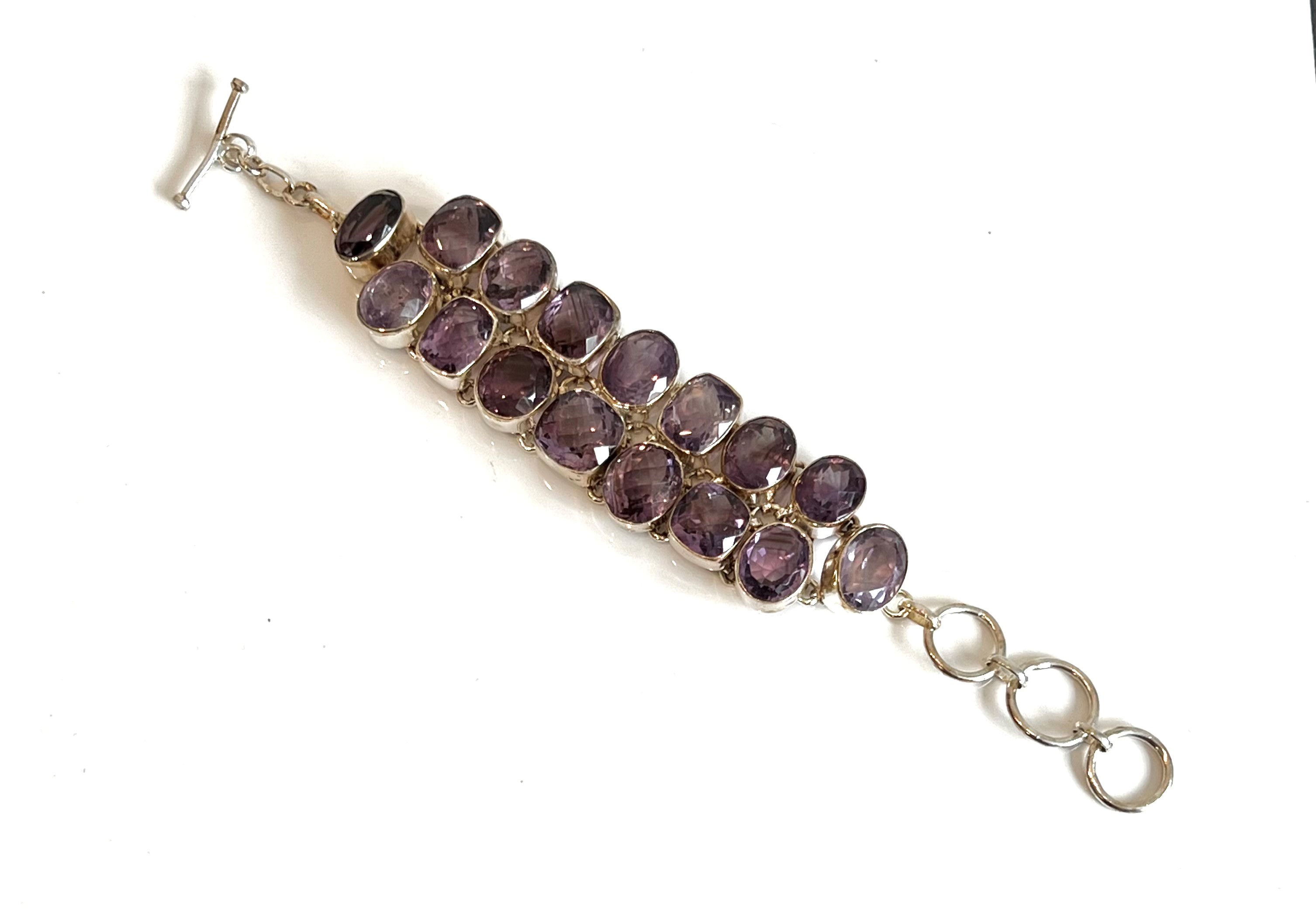 A sterling silver and amethyst bracelet - stamped 925, set with two rows of alternate oval and