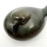 An Inuit carved stone sculpture of a resting bird - in green stone, its head huddled down on its