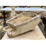 A composite stone planter in the shape of a wheelbarrow - marked ‘Cotswold Studios L2’ inside