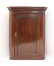 A George III oak wall-hanging corner cabinet - with cavetto moulded cornice, single panelled door