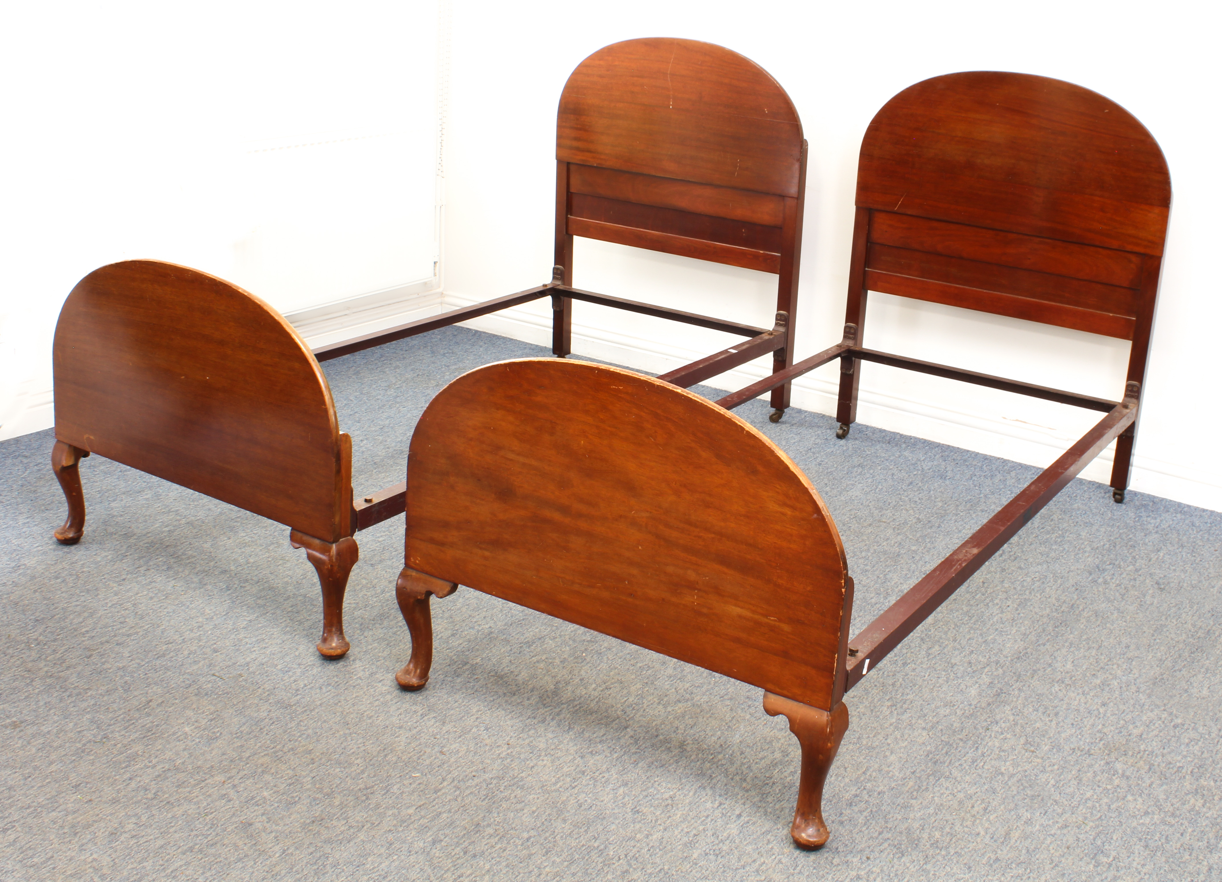 A pair of mid-century mahogany single beds - with arched head and foot boards, the footboards on