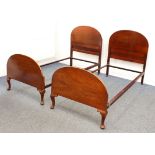 A pair of mid-century mahogany single beds - with arched head and foot boards, the footboards on