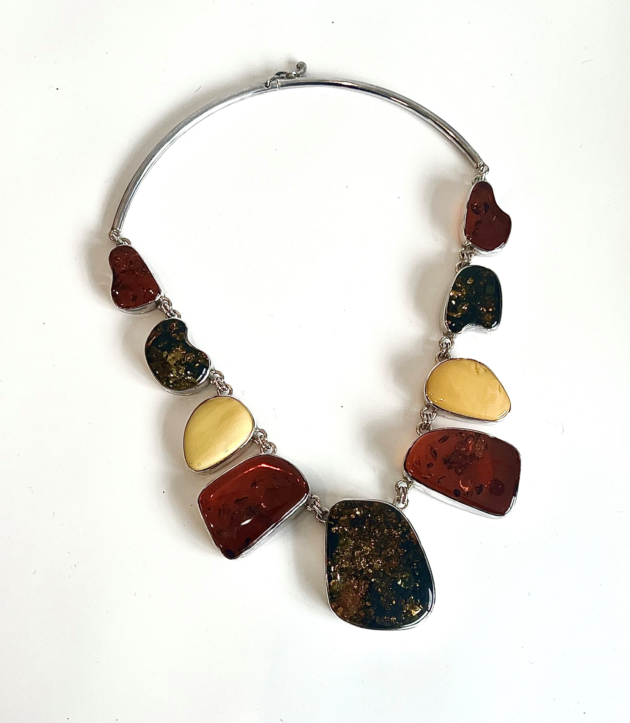 A silver and Baltic amber plaque necklace - with nine graduated asymmetric amber plaques, each rub-