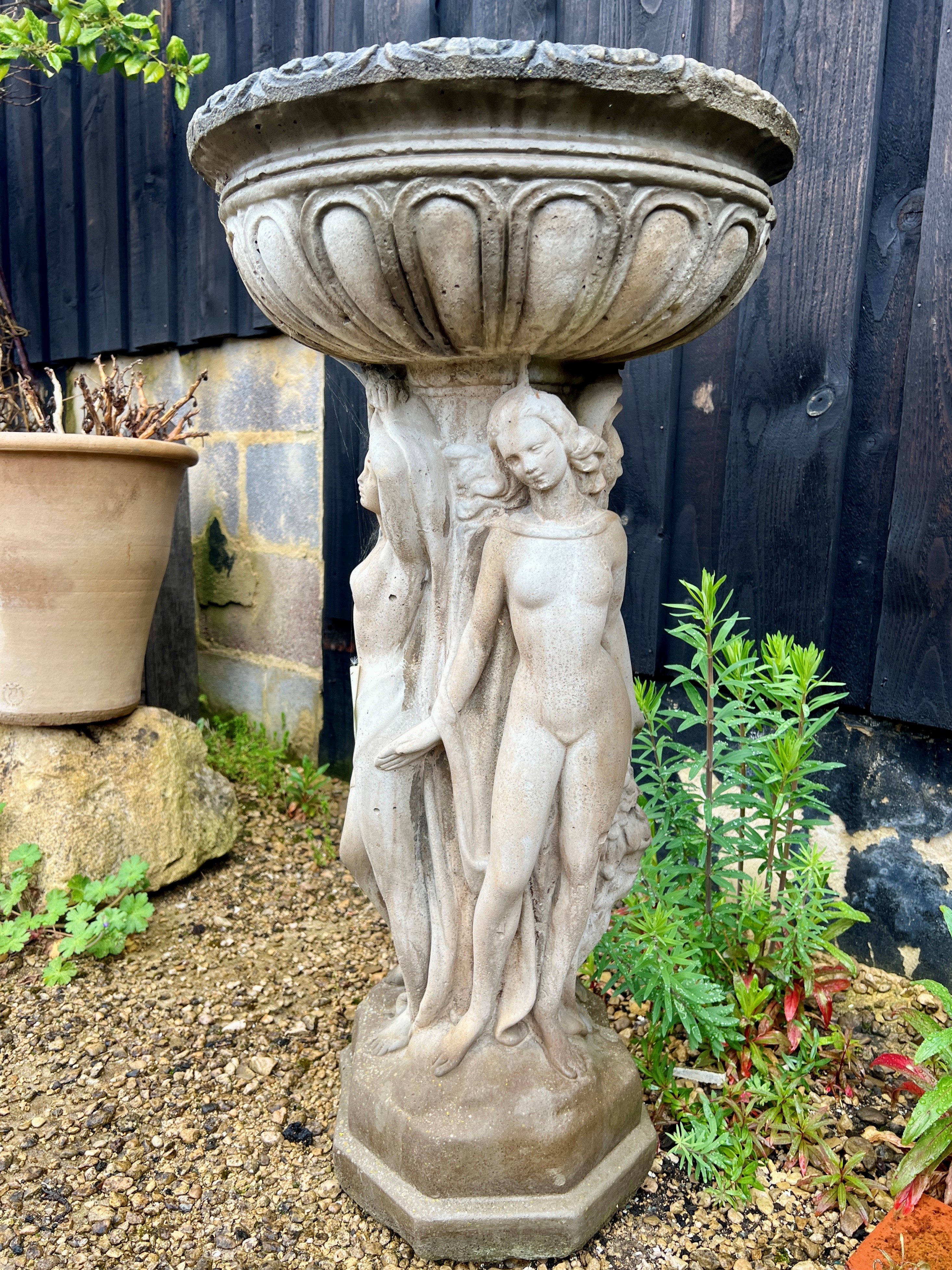 A composite stone bird bath - raised on a three graces style pedestal base, the bowl 46cm