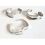 Three sterling silver modernist bangles of wavy form - one solid and the other two of pierced