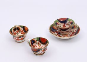 A mid-19th century miniature tea cup and saucer - painted with Imari style decoration, the saucer