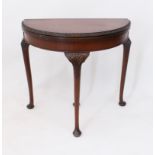 A 1920s-30s mahogany demi-lune card table - the fold over top with foliate carved edge and green