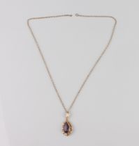 A 9ct gold and amethyst pendant - the pear cut amethyst, approx. 14.5 x 7.5mm, in a foliate scroll