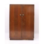 A 1940s-50s oak child's compactum wardrobe - striped veneered doors and inset plinth base, the