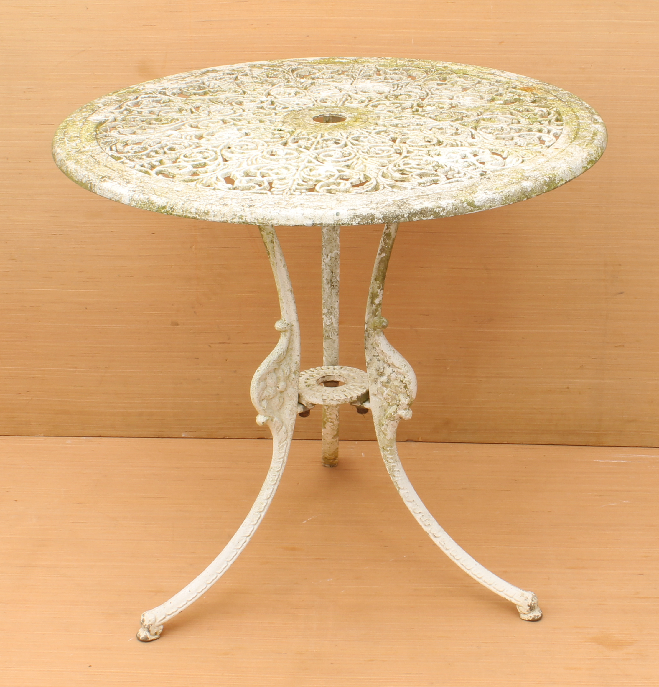 A cast metal garden table - circular, with pierced foliate scroll decoration, on three swept