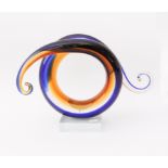 An art glass sculpture - of scrolled, spiral form, in dark-blue, amber and clear glass, each end