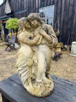 A composite stone statue of a young couple embracing - 70cm high.