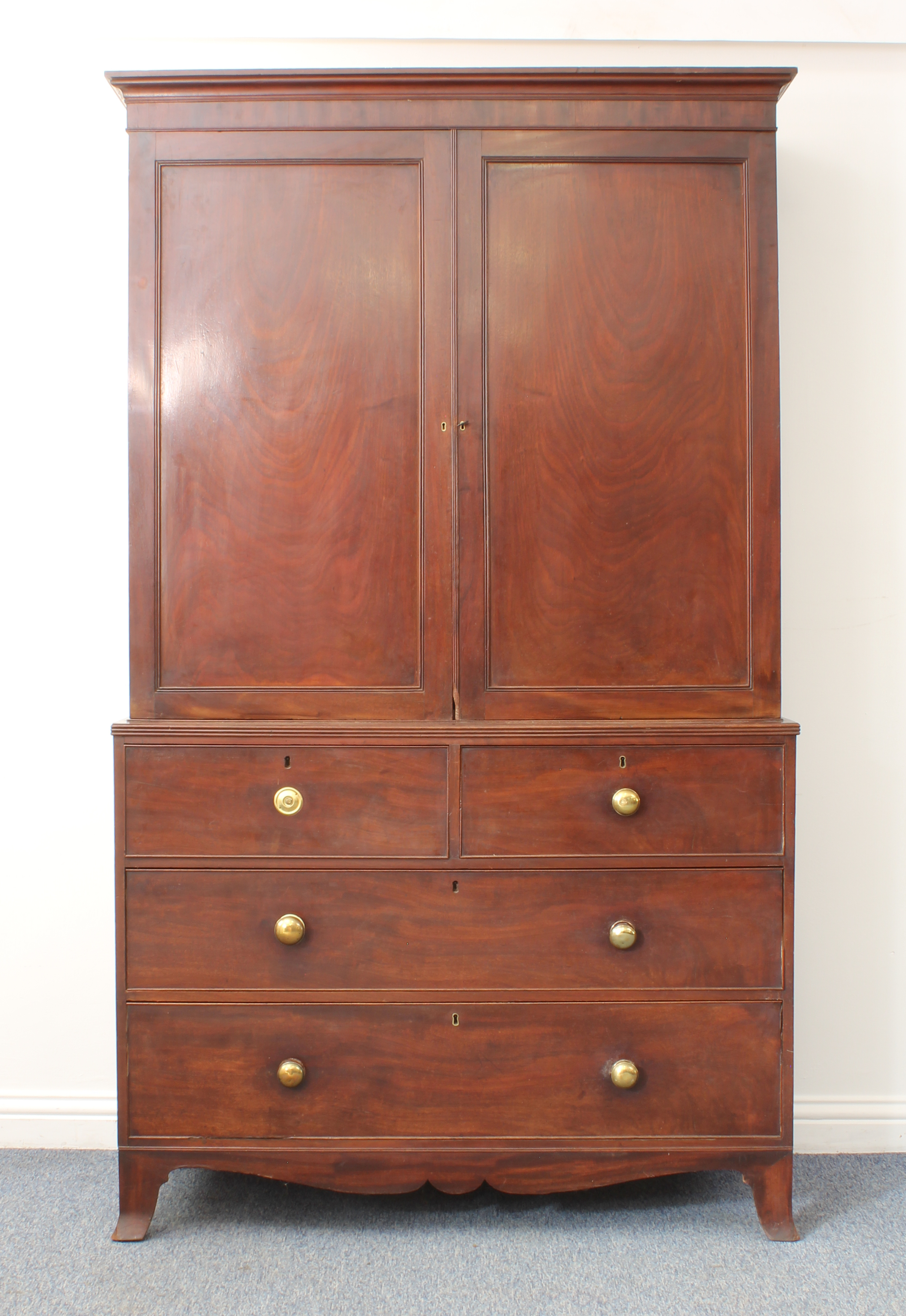 An early 19th century mahogany linen press - the moulded cornice over a pair of panelled doors,