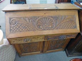 LATE 19TH CENTURY CARVED OAK BUREAU WITH FALL FRONT OVER 2 FRIEZE DRAWERS OVER 2 PANEL DOORS,