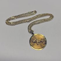 9CT GOLD ARIES CIRCULAR PENDANT DECORATED WITH LEAPING RAM ON A 9CT GOLD FLAT LINK CHAIN - 16.