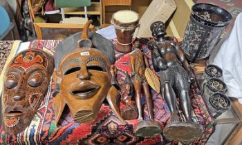 CARVED WOODEN TRIBAL MASKS AND FIGURES ALONG WITH TWO GLASS AND METAL CANDLE HOLDERS.